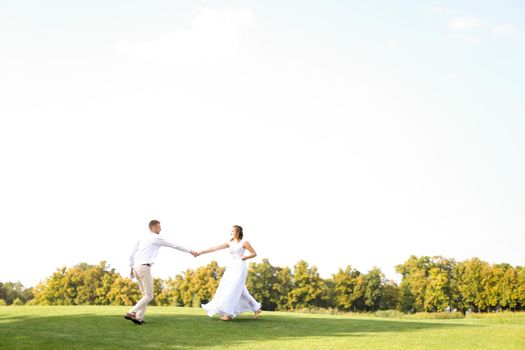 Groom and bride dancing and playing on grass. Concept of wedding photo session on open air and nature.