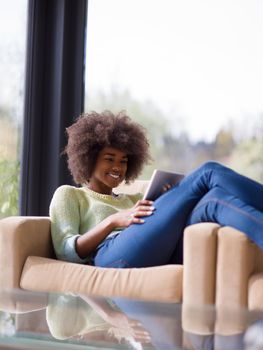 Young african american woman at home relaxing in her luxury lliving room reading a digital tablet  surf internet and work