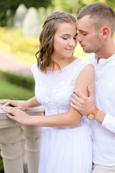 Happy pretty bride and groom holding hands and standing outdoors. Concept of relationship, wedding and bridal photo session.