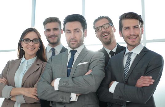 Team of successful happy businesspeople standing in office, businesswoman in front smiling.