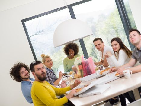 multiethnic group of happy friends spending time together with food and soda drinks, eating at home concept