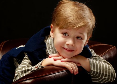 Beautiful little boy closeup. Studio portrait on black background. Concept layout for magazine cover.