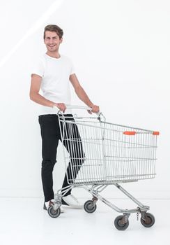 young man pushes an empty shopping cart. photo with copy space