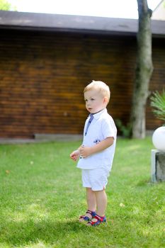 Little american baby standing on grass. Concept of childhood and summer.