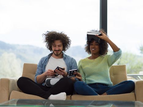 Multiethnic Couple using virtual reality headset in living room at home  people playing game with new trends technology