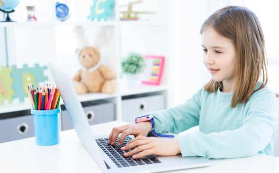 Cute little girl using computer in light room