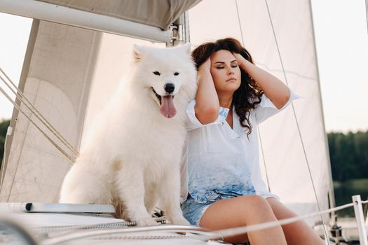 a happy woman with a big white dog on a white yacht in the sea.