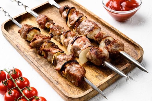 Shish kebab BBQ meat with onions and tomatoes set, on white stone table background