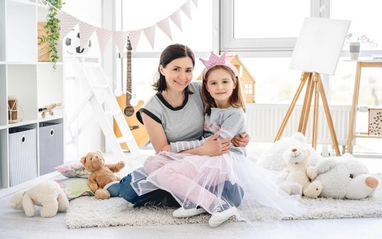 Happy mother holding cute daughter in bright decorated room