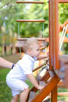 Little male baby playing on children playground. Concept of childhood and summer.