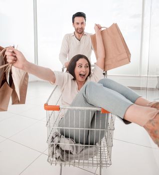 man carries his girlfriend in a shopping cart. photo with copy space