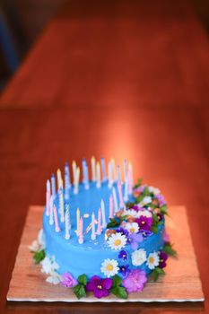 Blue isolated cake with candles on wooden background with copy space. Concept of sweet food for birthday party.