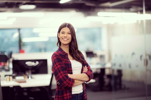 Portrait of young successful female software developer with with crossed arms at modern startup office