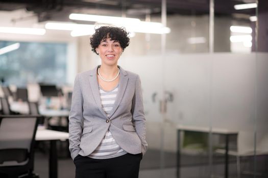 Portrait of successful female software developer with a curly hairstyle at modern startup office