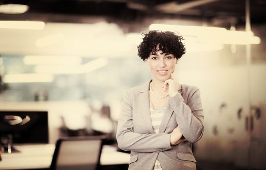 Portrait of successful female software developer with a curly hairstyle at modern startup office