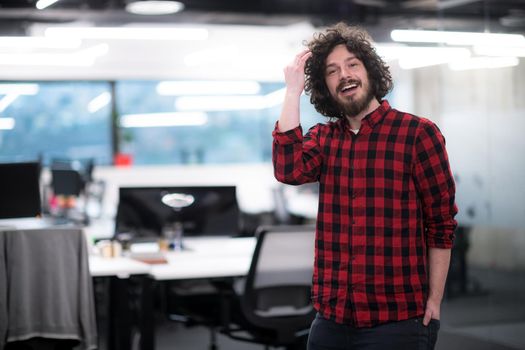 Portrait of young smiling successful male software developer standing at modern startup office