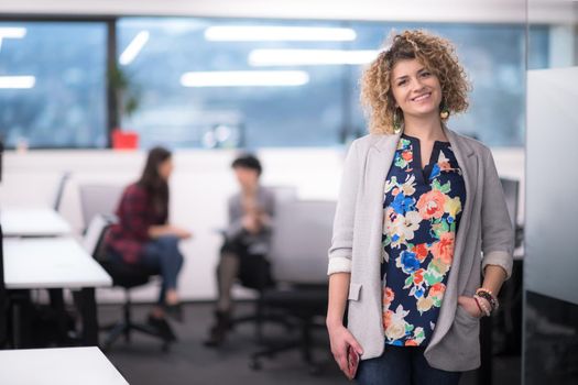 Portrait of successful female software developer with a curly hairstyle at modern startup office