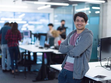 Portrait of young smiling successful male software developer standing at modern startup office