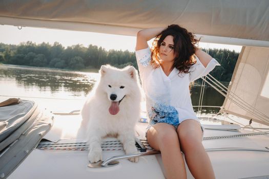 a happy woman with a big white dog on a white yacht in the sea.