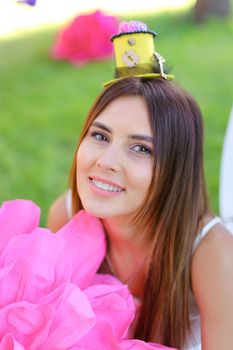 Portrait of young beautiful girl with big pink flower and hat as decoration. Concept of beauty and female person.