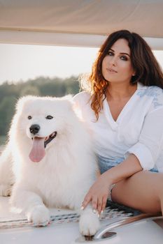 a happy woman with a big white dog on a white yacht in the sea.