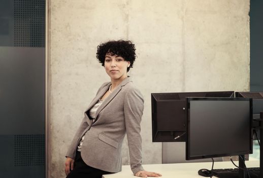 Portrait of successful female software developer with a curly hairstyle at modern startup office