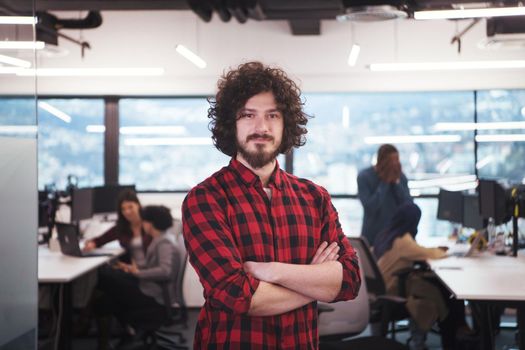 Portrait of young smiling successful male software developer standing at modern startup office