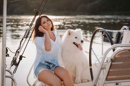 a happy woman with a big white dog on a white yacht in the sea.