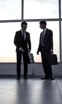 two businessmen talking standing in the office hall. business concept