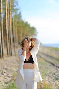 Caucasian girl walking on sand beach and wearing white shirt with black bra. Concept of summer vacations and fashion.