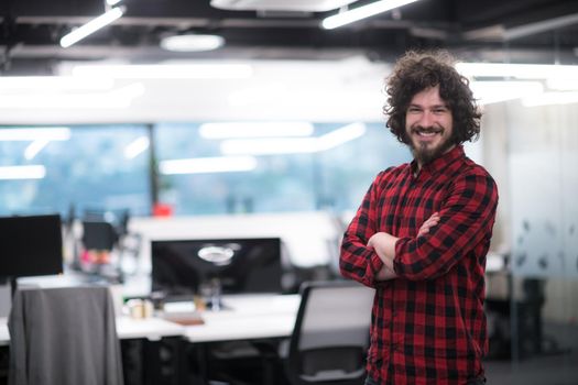 Portrait of young smiling successful male software developer standing at modern startup office