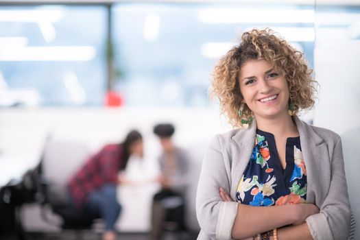 Portrait of successful female software developer with a curly hairstyle at modern startup office