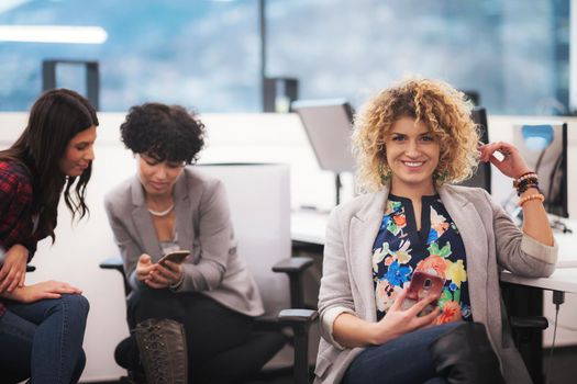 Portrait of successful female software developer with a curly hairstyle at modern busy startup office