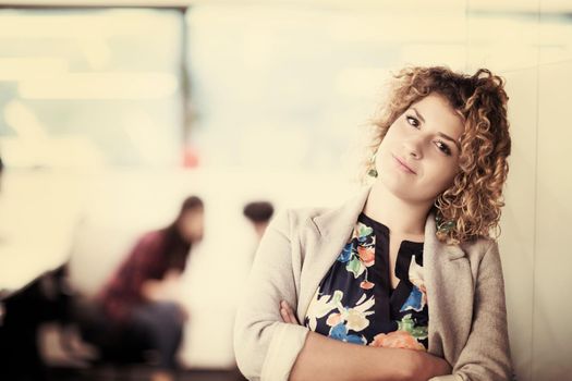 Portrait of successful female software developer with a curly hairstyle at modern startup office