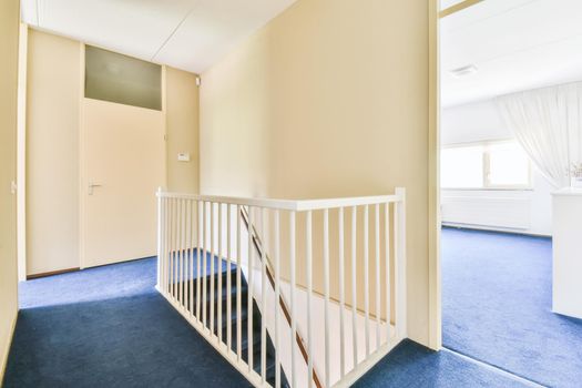 A room with a staircase leading down and a blue floor