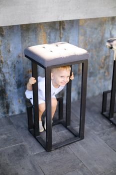 Little male baby wearing white clothes and playing outside. Concept of childhood.