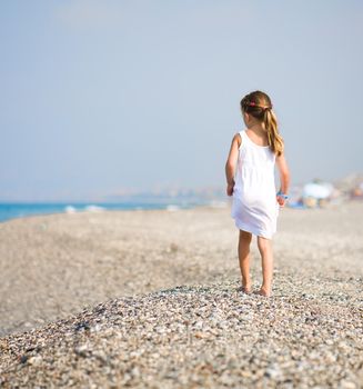 Back of a little girl on tropical beach vacation