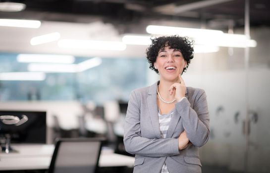 Portrait of successful female software developer with a curly hairstyle at modern startup office