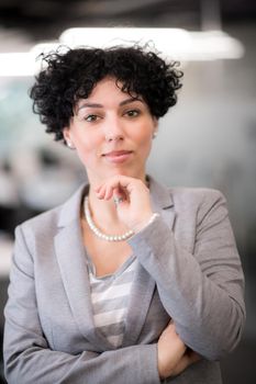 Portrait of successful female software developer with a curly hairstyle at modern startup office