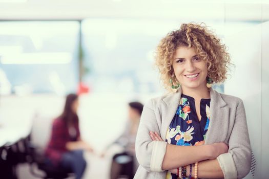 Portrait of successful female software developer with a curly hairstyle at modern startup office