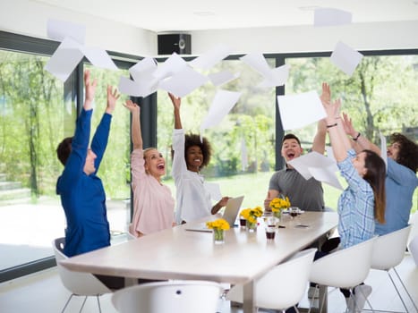 multiethnic Group of young business people throwing documents and looking happy while celebrating success at their working places in startup office