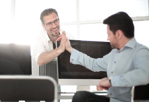 employees give each other a high five over the computer Desk. success concept