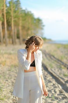 Nice female person walking on sand beach and wearing white clothes. Concept of summer vacations.