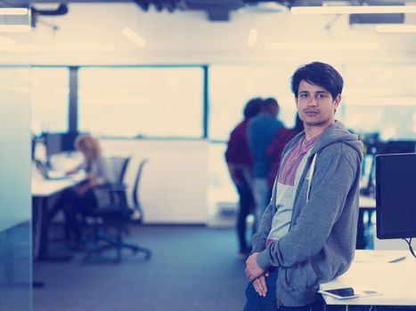 Portrait of young smiling successful male software developer standing at modern startup office