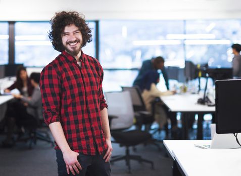 Portrait of young smiling successful male software developer standing at modern startup office