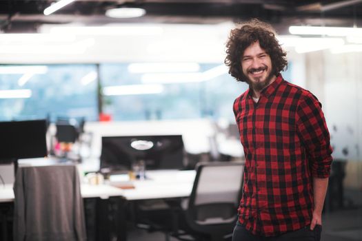 Portrait of young smiling successful male software developer standing at modern startup office