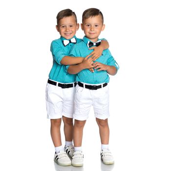 Two cute little boys stand in front of the camera in full growth. The concept of a happy childhood, the development of a child in the family. Isolated on white background.