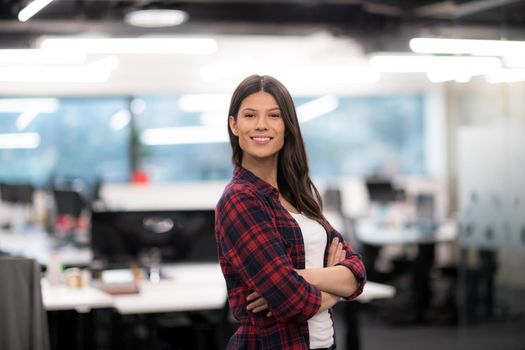 Portrait of young successful female software developer with with crossed arms at modern startup office