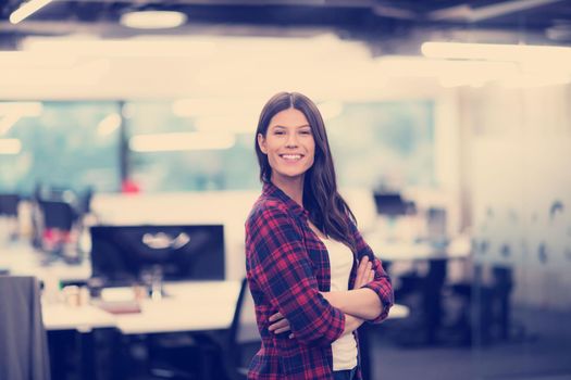 Portrait of young successful female software developer with with crossed arms at modern startup office