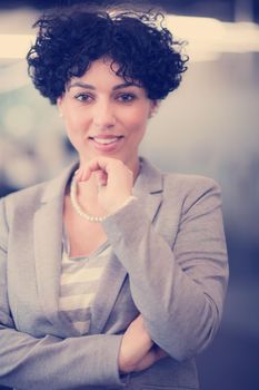 Portrait of successful female software developer with a curly hairstyle at modern startup office